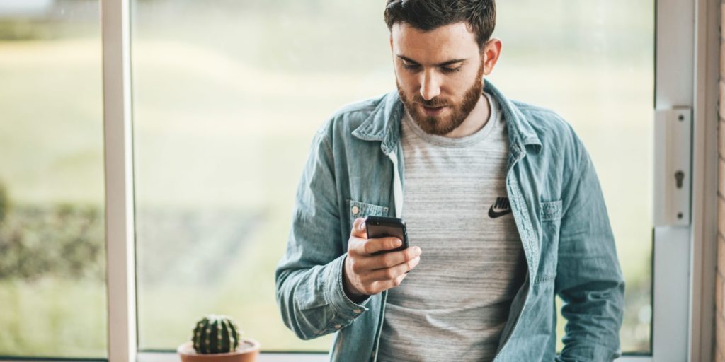 Bearded man looking down at his mobile phone.